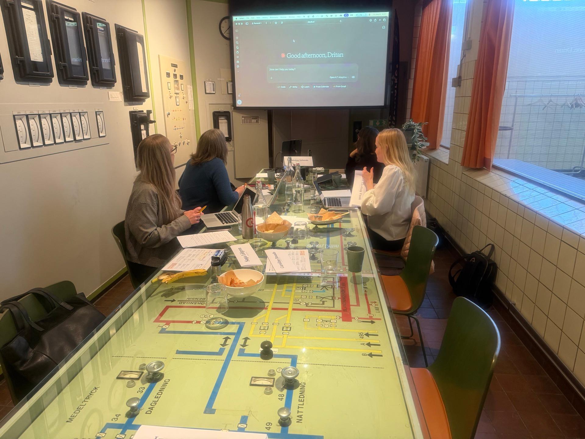 Attendees at the first Innovaiden Stockholm workshop working on their own ideas around the long table while Dritan presents Claude on screen.